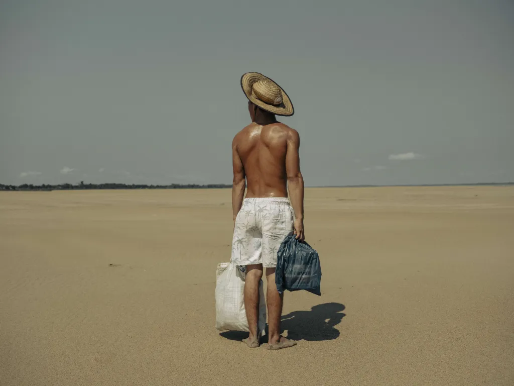 Finalista World Press Photo 2025 – Amazonské sucho (Droughts in the Amazon) – Mladý muž nosí jídlo své matce, která žije ve vesnici Manacapuru v brazilské Amazonii. Vesnice byla kdysi přístupná lodí, ale kvůli suchu nyní musí jít dva kilometry podél vyschlého koryta řeky Solimões, aby se k matce dostal