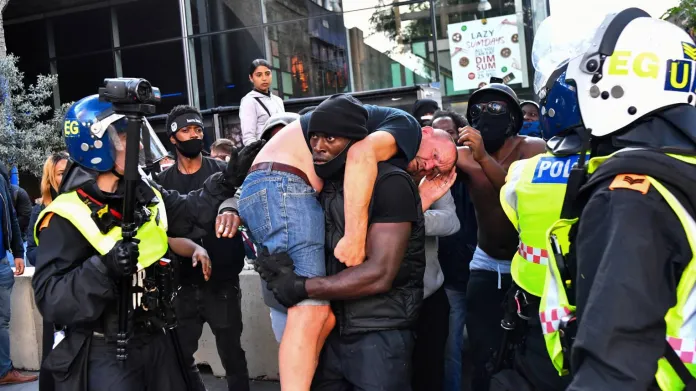 Fotka protestujícího, nesoucího zraněného bělocha, se dostala na titulní strany britských novin