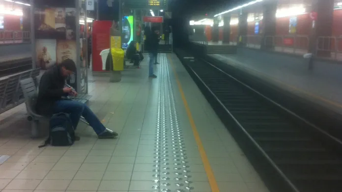 Poloprázdná stanice metra a všichni v ruce drží telefony