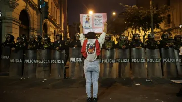 Protestující zahalená do peruánské vlajky před zástupem policistů na jedné z demonstrací (20. září 2025)