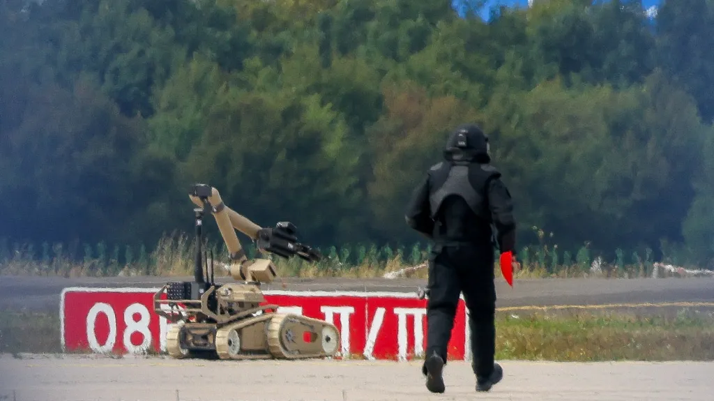 Policista v ochranném oděvu vedle robota pro zneškodňování výbušnin na německém letišti Lipsko/Halle