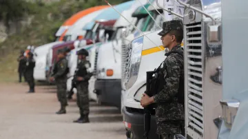 Členové bezpečnostních sil střeží nákladní vozy s volebními urnami