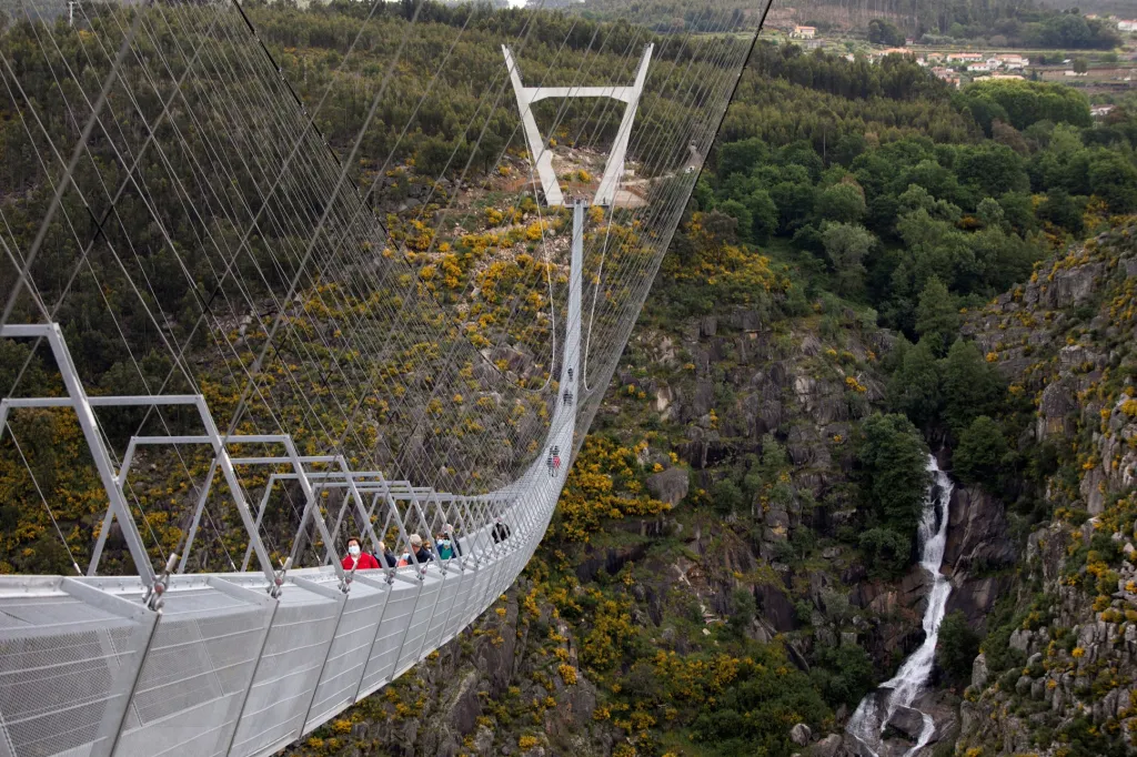 Lidé jdou po nejdelším visutém mostě na světě nazvaným „516 Arouca“. Ten je nově otevřený u portugalského města Arouce. Konstrukce přemosťuje 175 metrů hluboké údolí řeky Paiva. Délka mostu je ukrytá přímo v jeho názvu - měří tedy 516 metrů