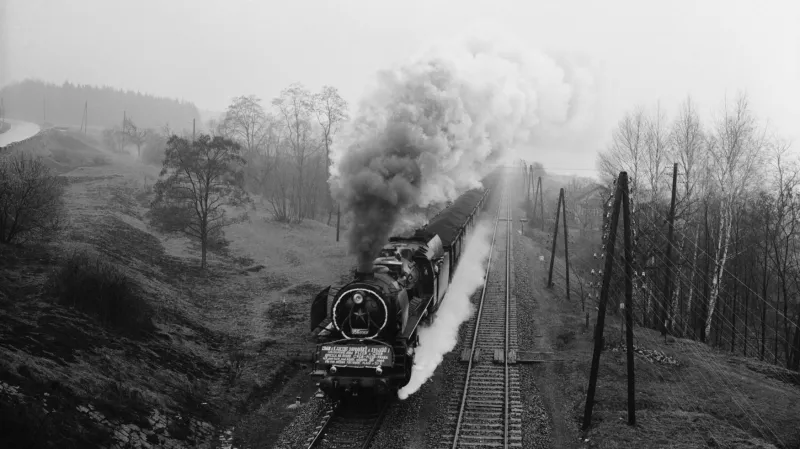 Těžkotonážní hnutí se v 50. letech nevyhnulo ani trati z Plzně do Prahy. Cedule na lokomotivě hlásá, že mohutný nákladní vlak ušetřil jízdu 28 běžných vlaků. Z pohledu strojvedoucího bylo nepochybným důkazem velkého umění, že něco takového dokázal s parní lokomotivou. Kolejím to však nesvědčilo, problém s těžkotonážními vlaky byl i ten, že se nevešly na nádraží.