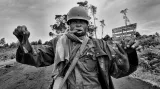 Voják konžské armády drží lidskou ruku a pohlavní orgány, které právě nožem odřízl jednomu z mrtvých bojovníků Národního kongresu pro obranu lidu. Demokratická republika Kongo, listopad 2008