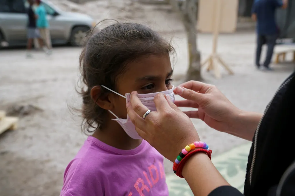 Lékárnice vysvětluje sedmileté Perle, jakým způsobem si roušku nasadit, aby její používání bylo efektivní