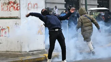 Demonstrant odhazuje náboj se slzným plynem