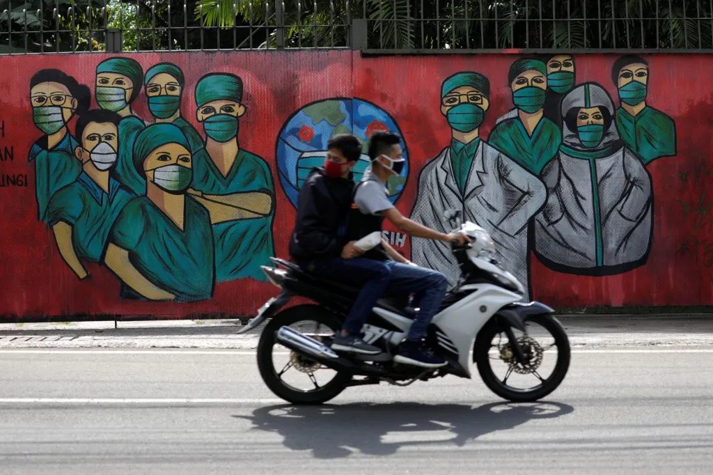 Současná pandemická situace se pomalu začíná projevovat v umění. Kolem stěny s malbou projíždí moped v indonéské Jakartě