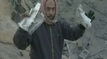 Palestinec vytahuje z trosek domu roztrhaný Korán