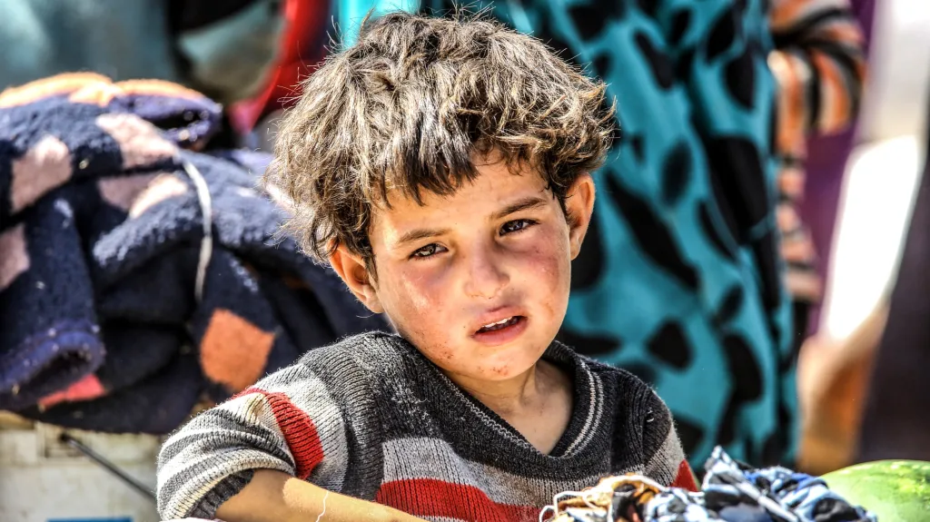 Syrské dítě pozoruje lidi prchající před boji mezi islamisty a Kurdy ve městě Tal Abyad