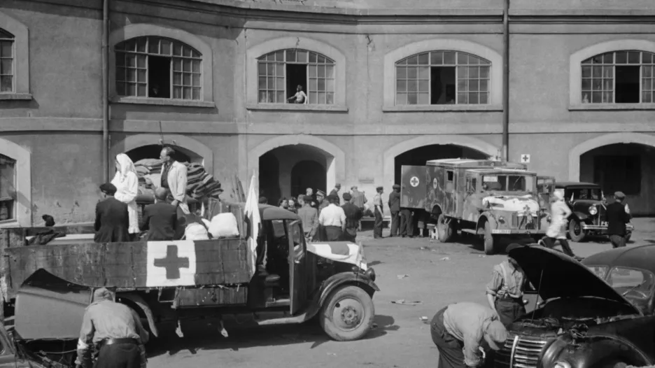 Snímek pořídil Josef Vosolsobě, který se zúčastnil prací expedice vyslané 9. května 1945 do Terezína. Dobový popis: „ Pomocné expedice z Prahy organizuje zdravotní komise Národní rady pod vedením obětavého pracovníka, který má nemalé zásluhy o celou akci, MUDr.Karla Rašky. Desítky aut přivážejí do Terezína nutná léčiva, potraviny i pomocný personál.“