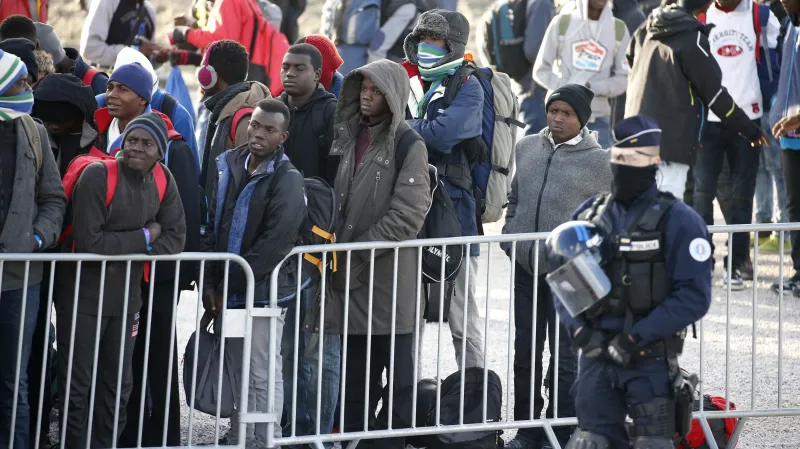 Nezletilí migranti v bývalém táboře u Calais čekají na autobus