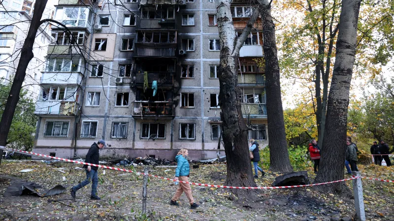 Místní obyvatelé se procházejí kolem své několikapatrové budovy poškozené výbuchem dronu v Kyjevě 30. října 2024 během ruské invaze na Ukrajině