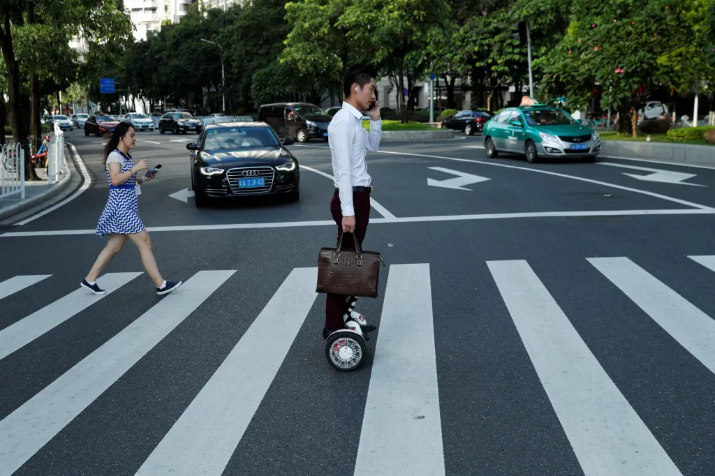 Muž jede do práce na hoverboardu neboli kolonožce v obchodní čtvrti v Kantonu v Číně