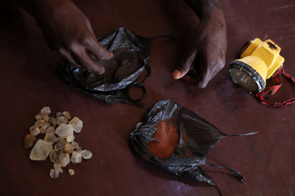 Horník vystavuje minerály, které našel v dole v nigerijském městě Josu, který se nachází uprostřed rezidenční zástavby