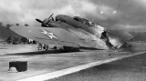 Trosky amerického bombardéru B-17 na letišti v Hickamu krátce po skončení bleskového japonského útoku na americkou námořní základnu Pearl Harbor. Tento letoun, pilotovaný kapitánem Swensonem, byl jedním z těch, které vyrazily na místo z Kalifornie. Po přistání se nevyhnul sprše padajících bomb