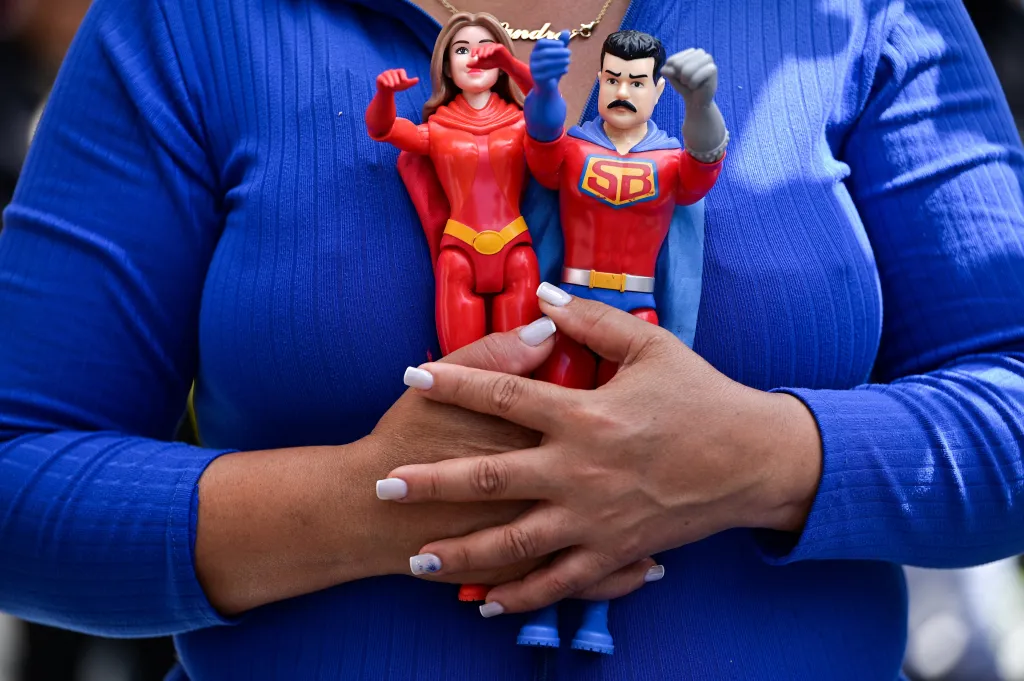 Podporovatelka Madurova režimu drží akční figurky inspirované venezuelským vládcem a jeho manželkou (Caracas)