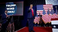Donald Trump gestikuluje, zatímco jeho syn Eric Trump tleská vedle něj během noční volební párty v Iowě