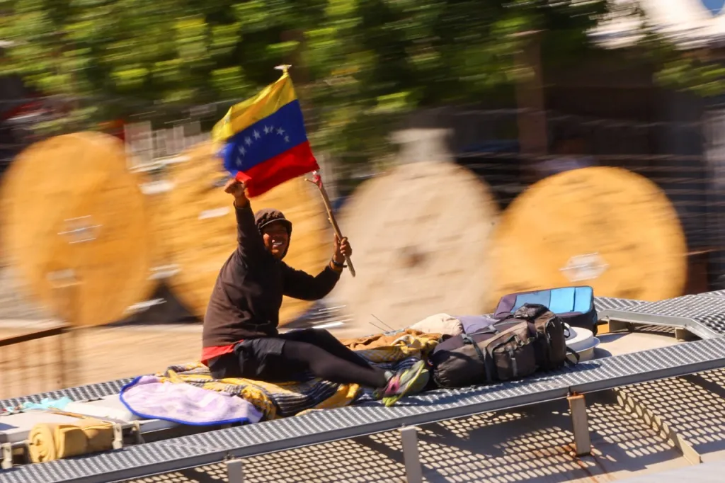 Muž na střeše vlaku s vlajkou Venezuely