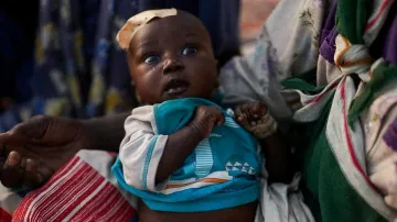 Žena drží dítě v táboře pro osoby, které uprchly ze súdánského Fáširu