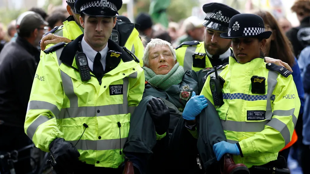 Policisté odnáší jednu z protestujících z hnutí Vzpoura proti vyhynutí
