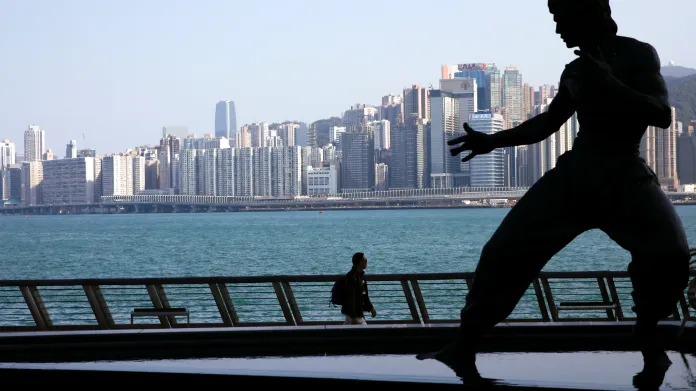 Panorama Hongkongu v kontrastu sochy herce Bruce Leeho