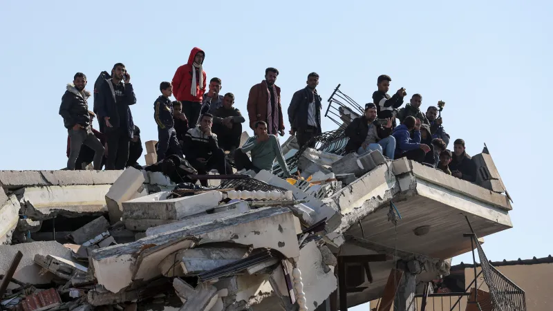 Palestinci přihlížejí předání rukojmí v Chán Júnisu na zřícené budově