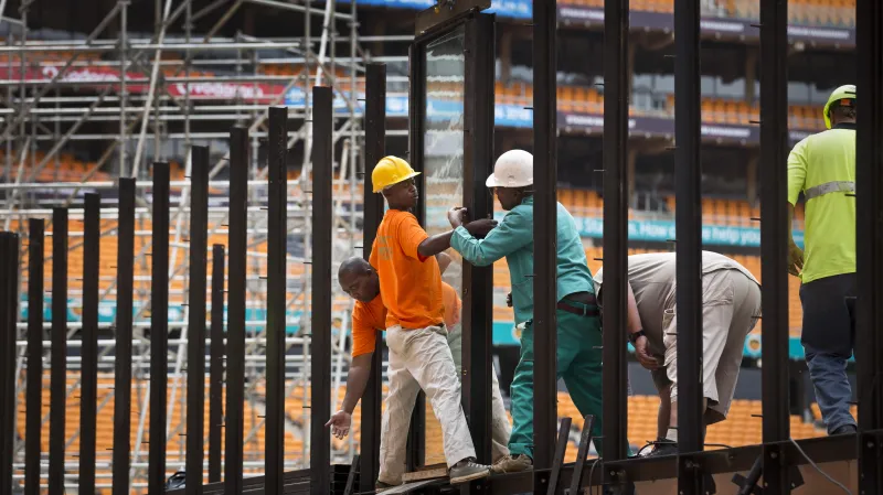 Pracovníci instalují neprůstřelné sklo, které bude obklopovat jeviště na stadionu