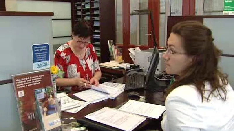 Zaměstnankyně banky pomáhá vyplnit klientce smlouvy.