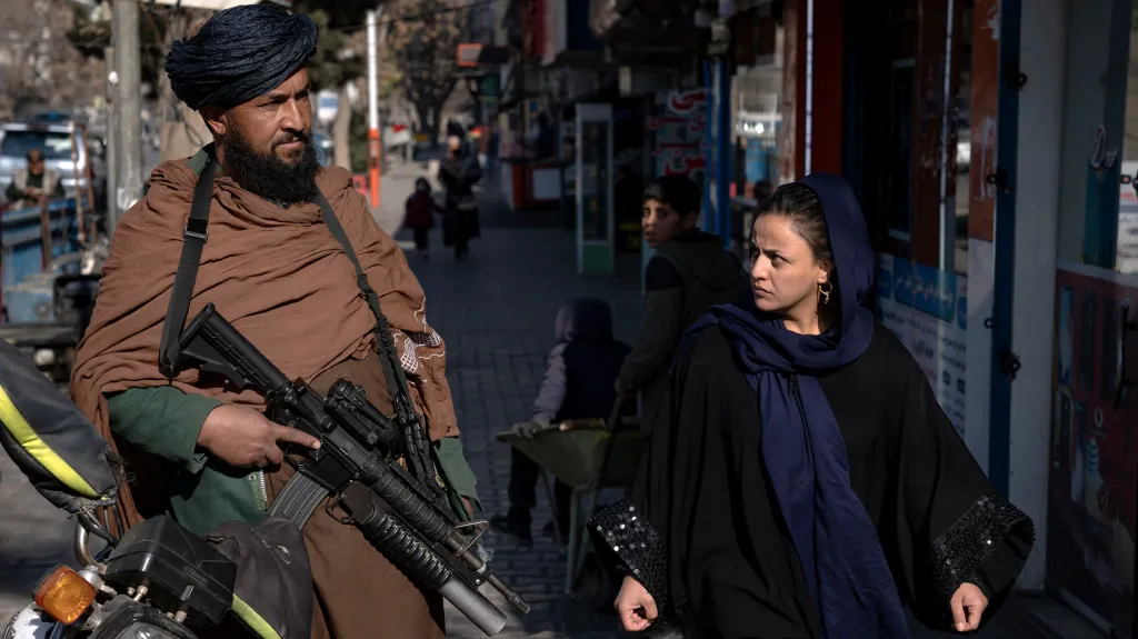 Afghánka prochází kolem hlídkujícího Taliba