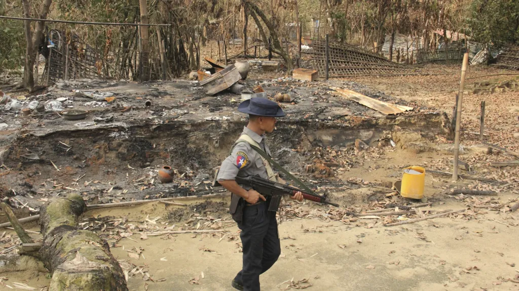 Voják v Myanmaru prochází kolem spálených domů Rohingů