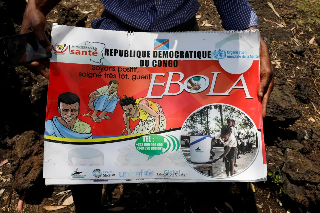 Dobrovolník ukazuje plakát s informacemi, které upozorňují na šíření viru ebola.