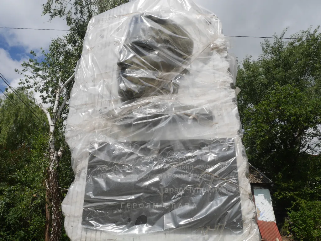 Zakonzervovaná pamětní stéla v Bilohoršči s vyobrazením Tarase Čuprynky, jak zněl dobový generálův pseudonym, před domem, odkud v posledních letech svého života řídil operace ukrajinského podzemí