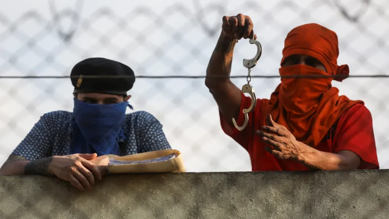 Vězeň stojí u bezpečnostní věže v guatemalské věznici Renovacion 1 a drží odemčená pouta