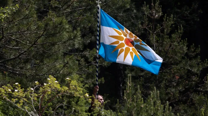 Protestant drží řeckou vlajku se symbolem Verginského slunce