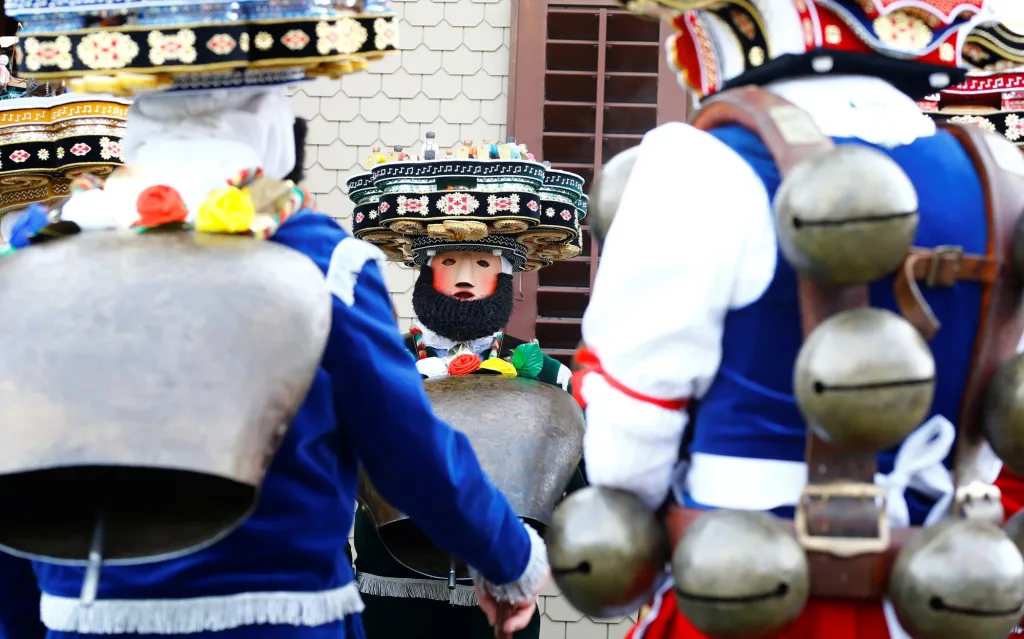 Muži oblečení v kostýmu postaviček "Chlaeuse"putují vesnicí Urnaesch ve Švýcarsku