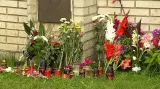 Lidé pokládají před dům obětí svíčky a květiny