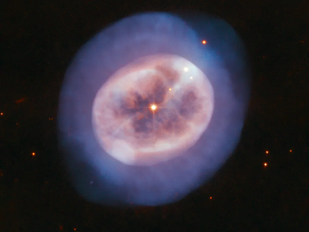 Stárnoucí hvězdu NGC 2022 v souhvězdí Orionu obklopuje oblak plynu tvarem připomínající medúzu. Snímek pořízený Hubbleovým vesmírným dalekohledem v srpnu 2019 ukazuje, jak se v tomto plynu odráží ultrafialové světlo hvězdy
