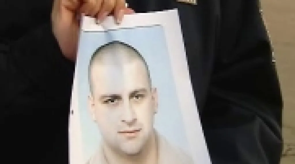 Policista ukazuje protrét hledaného Františka Procházky