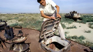 Fotografie z roku 1995 zachycuje ekologa Kosnazarova, jak otevírá zrezivělý poklop lodi. Ta je jednou z mnoha, která uvázla na bývalém dně Aralského jezera