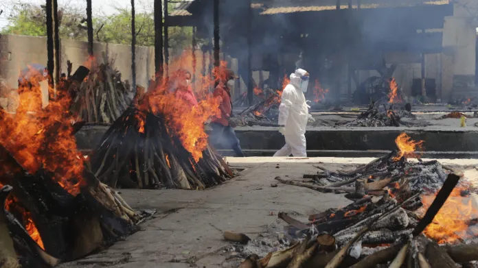 Pracovníci indických úřadů zapalují pohřební ohně s nakaženými