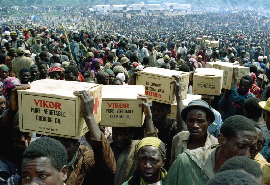 Rwandští uprchlíci přepravují zásoby potravin z distribučního místa v uprchlickém táboře Kibumba 28. července 1994 poté, co Červený kříž dopravil potraviny do tábora. V táboře bylo v této době kolem 400 tisíc uprchlíků