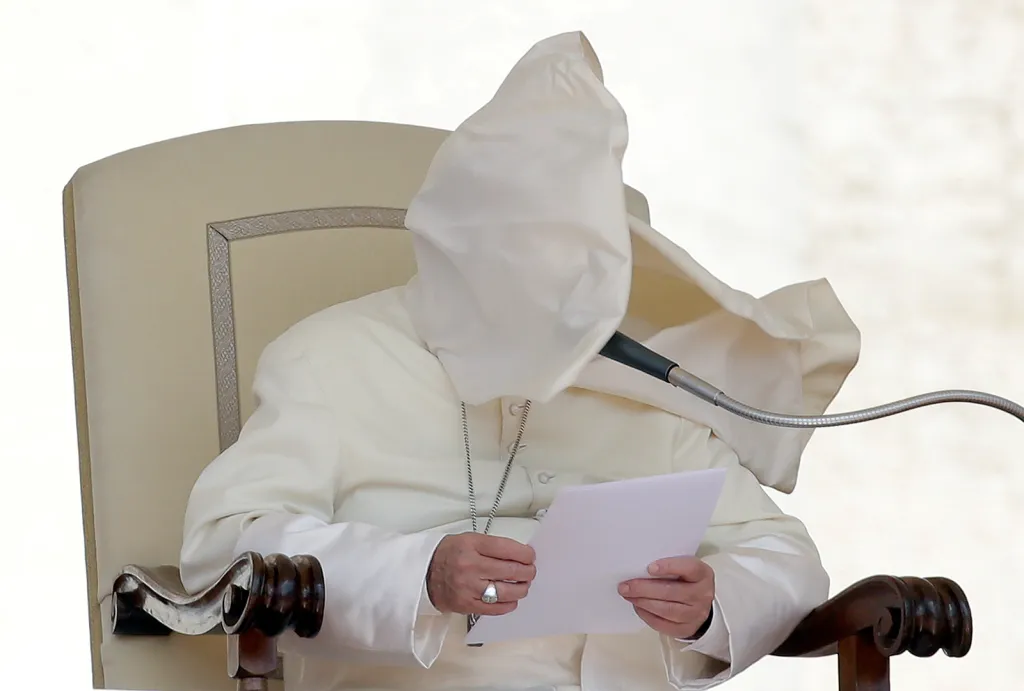 Poryv větru zvedá límec pláště a zahaluje obličej papeži Františkovi během mše na Svatopetrském náměstí ve Vatikánu