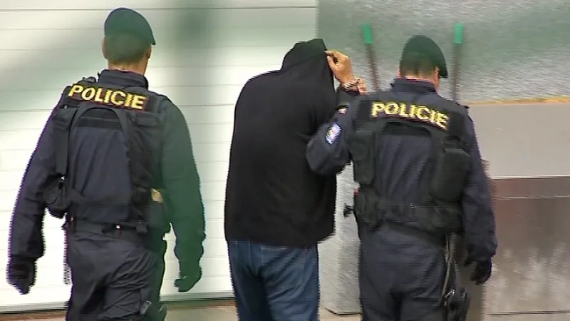 Policisté odvádí zadrženého muže