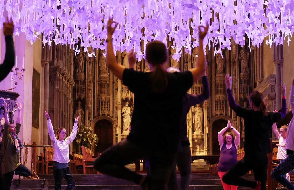 Lidé cvičí jógu pod tisíc let starou věží katedrály sv. Albana v Anglii