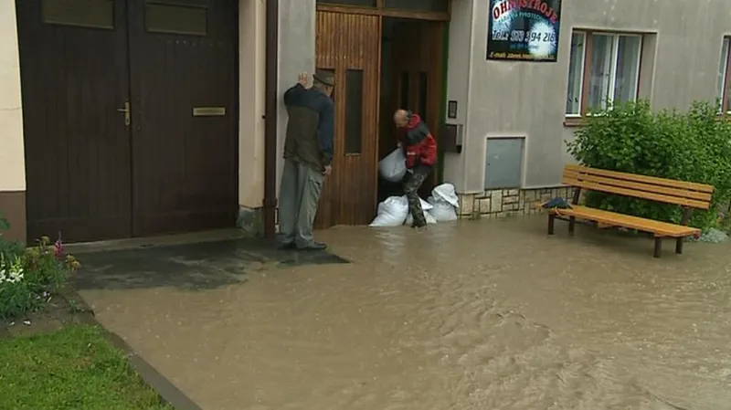Muž staví protipovodňovou hráz z pytlů s pískem