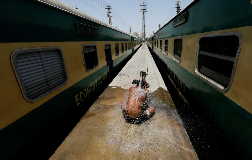Jeden z pracovníkú pakistánských železnic se sprchuje během horkého počasí. Země začala po ukončení nouzového stavu obnovovat dopravní spojení mezi jednotlivými městy