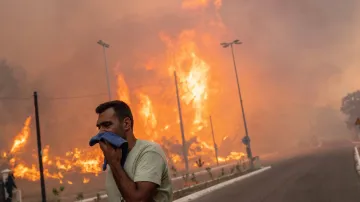 Dobrovolník si chrání dýchací cesty před kouřem. Foceno 22. srpna 2023