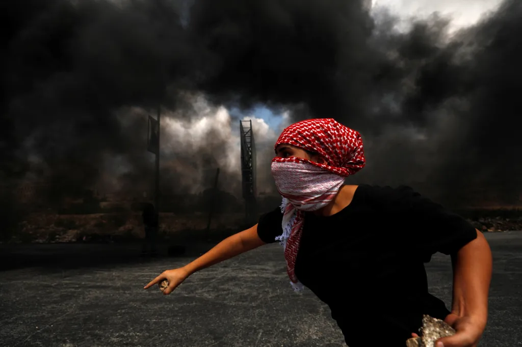 Palestinec se chystá hodit kamenem během demonstrace u osady Bejt El na Západním břehu Jordánu