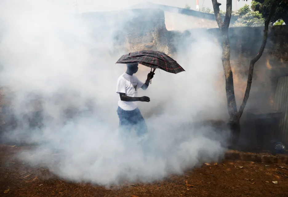 Muž prochází dýmem, který ho vyhnal z ulice, když projížděl dezinfekční vůz. Ten pomáhá v boji proti šíření choroby COVID-19 ve slumech Kibera v Nairobi
